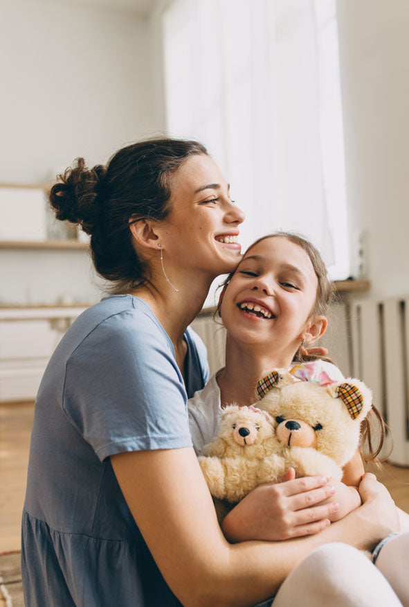 Mother and daughter at home, representing a maternity DNA test using a simple cheek swab kit.